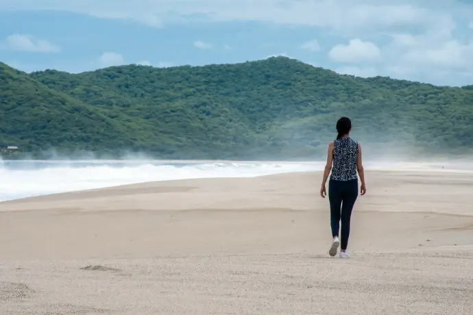 woman in black and white dress walking on seashore during daytime